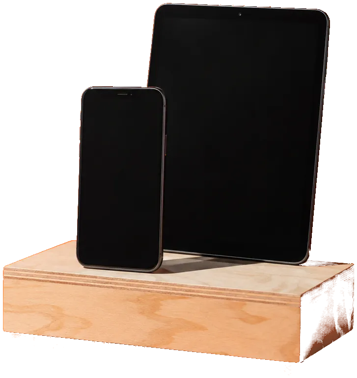 Een telefoon en een tablet, rechtop op een houten blok